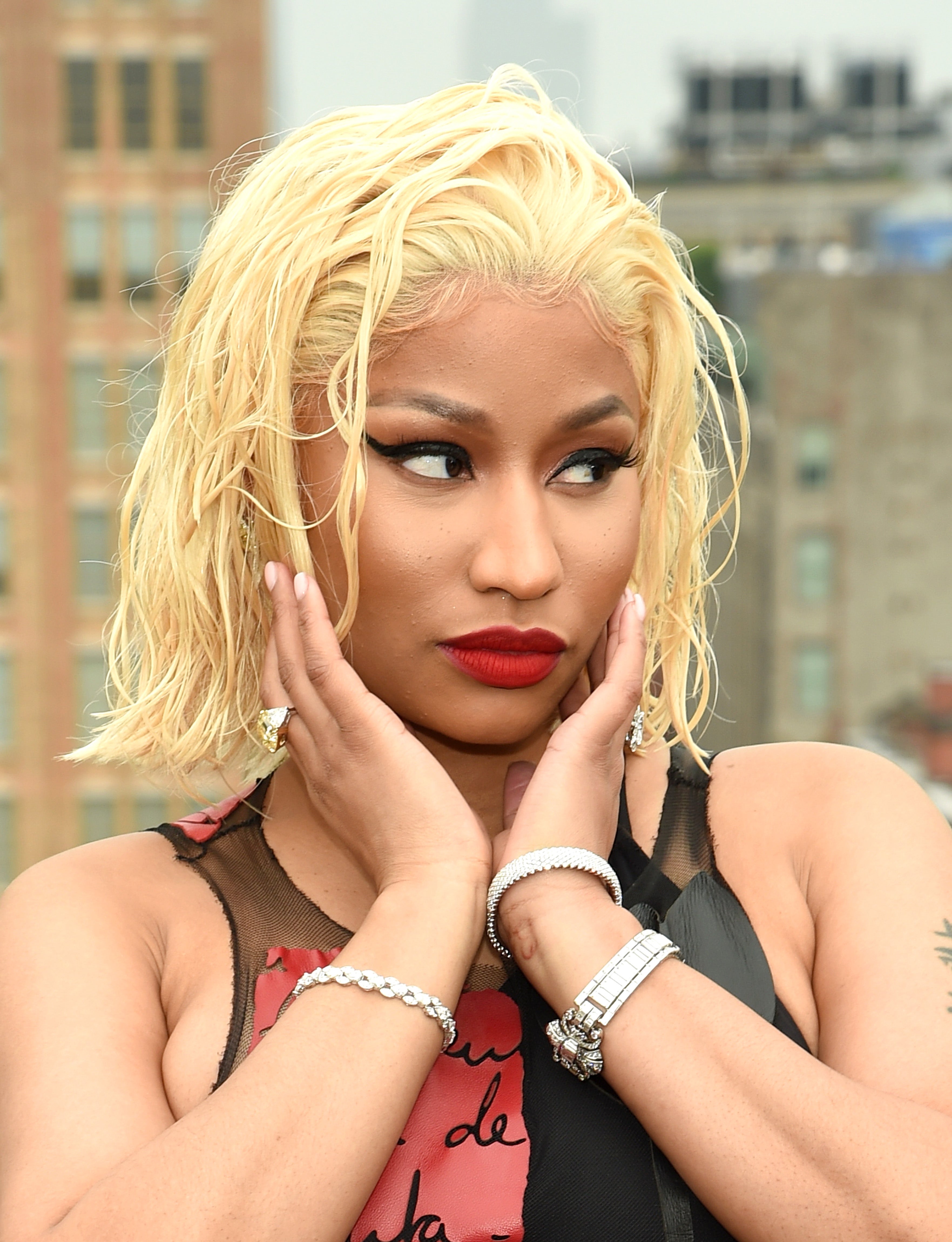 Nicki Minaj with short, slicked-back hairsbreadth successful a sleeveless outfit poses outdoors, accessorized with bracelets and brushed makeup