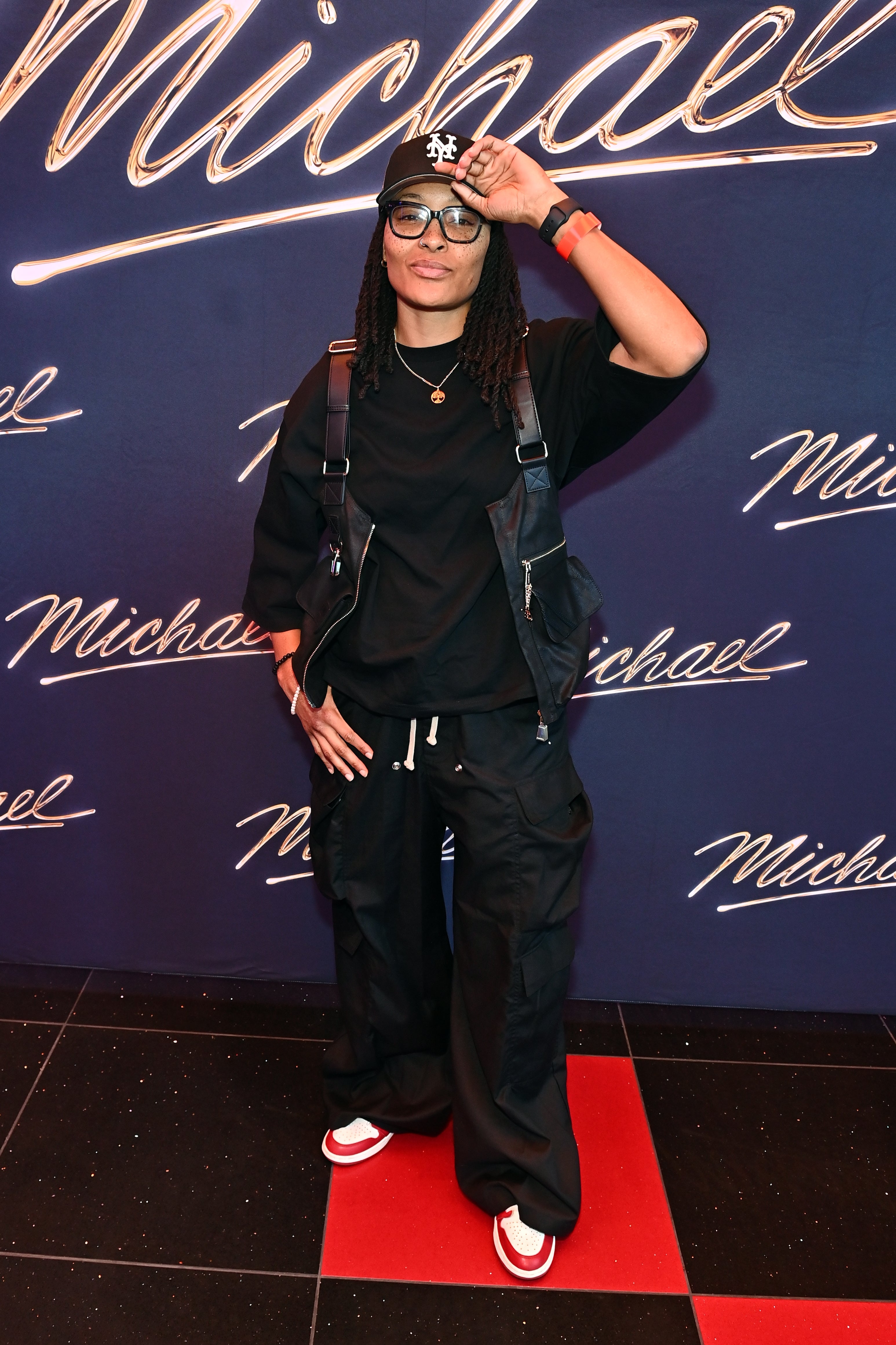 Person successful  casual outfit with a achromatic  headdress  and glasses, lasting  against a inheritance  with "Michael" written aggregate  times