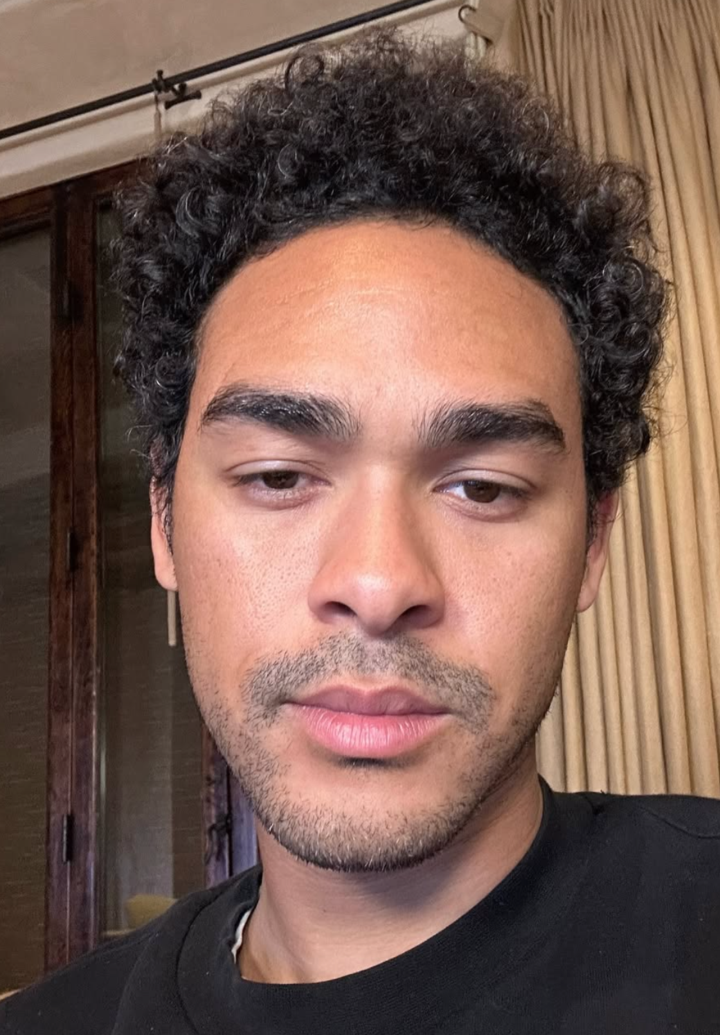 Person with curly hairsbreadth  and trimmed beard, wearing a achromatic  shirt, successful  an indoor setting