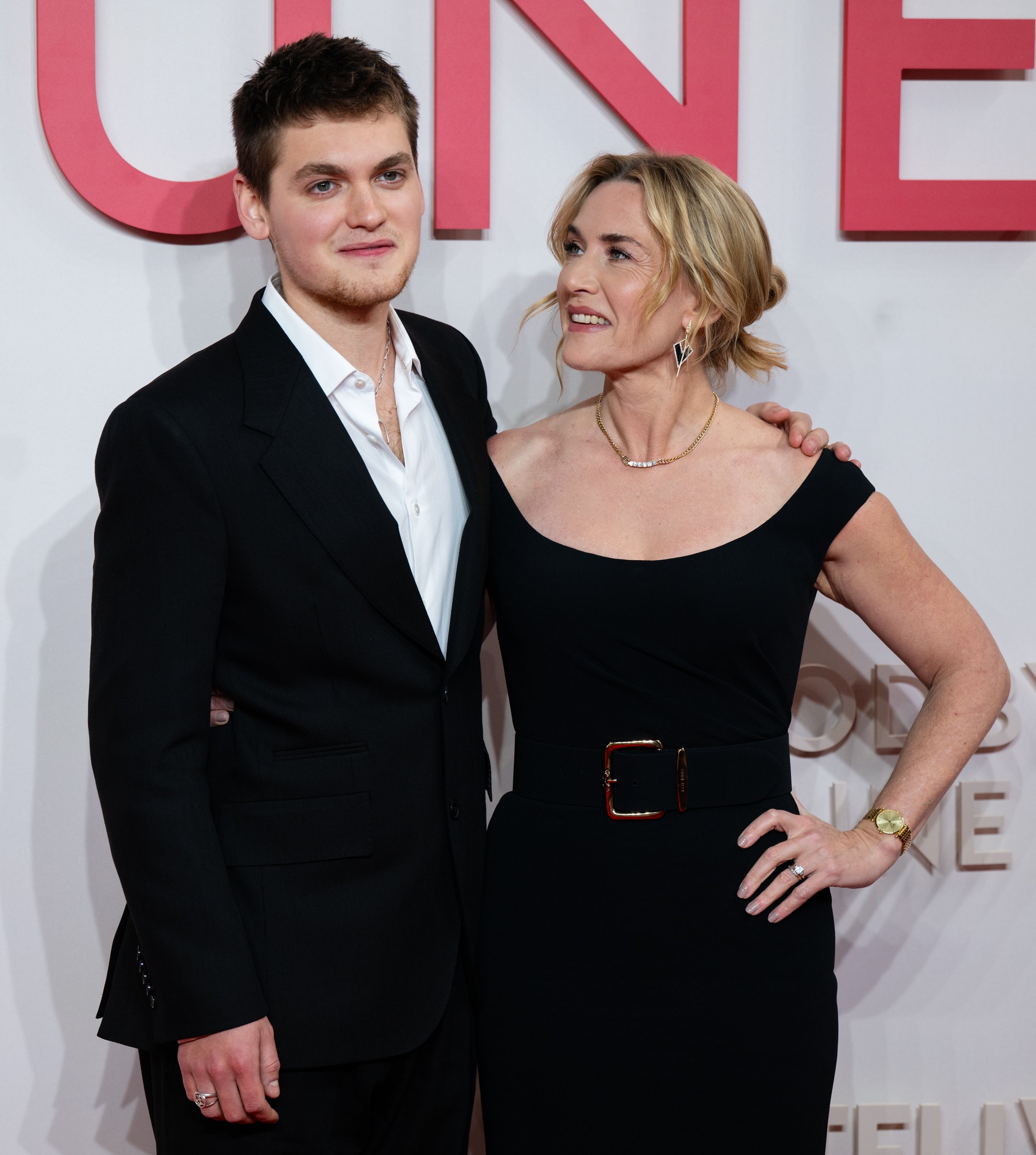 Two individuals connected  a reddish  carpet; the pistillate   is successful  a blase  achromatic  off-shoulder dress, the antheral   successful  a classical  achromatic  suit   with an open-collared shirt