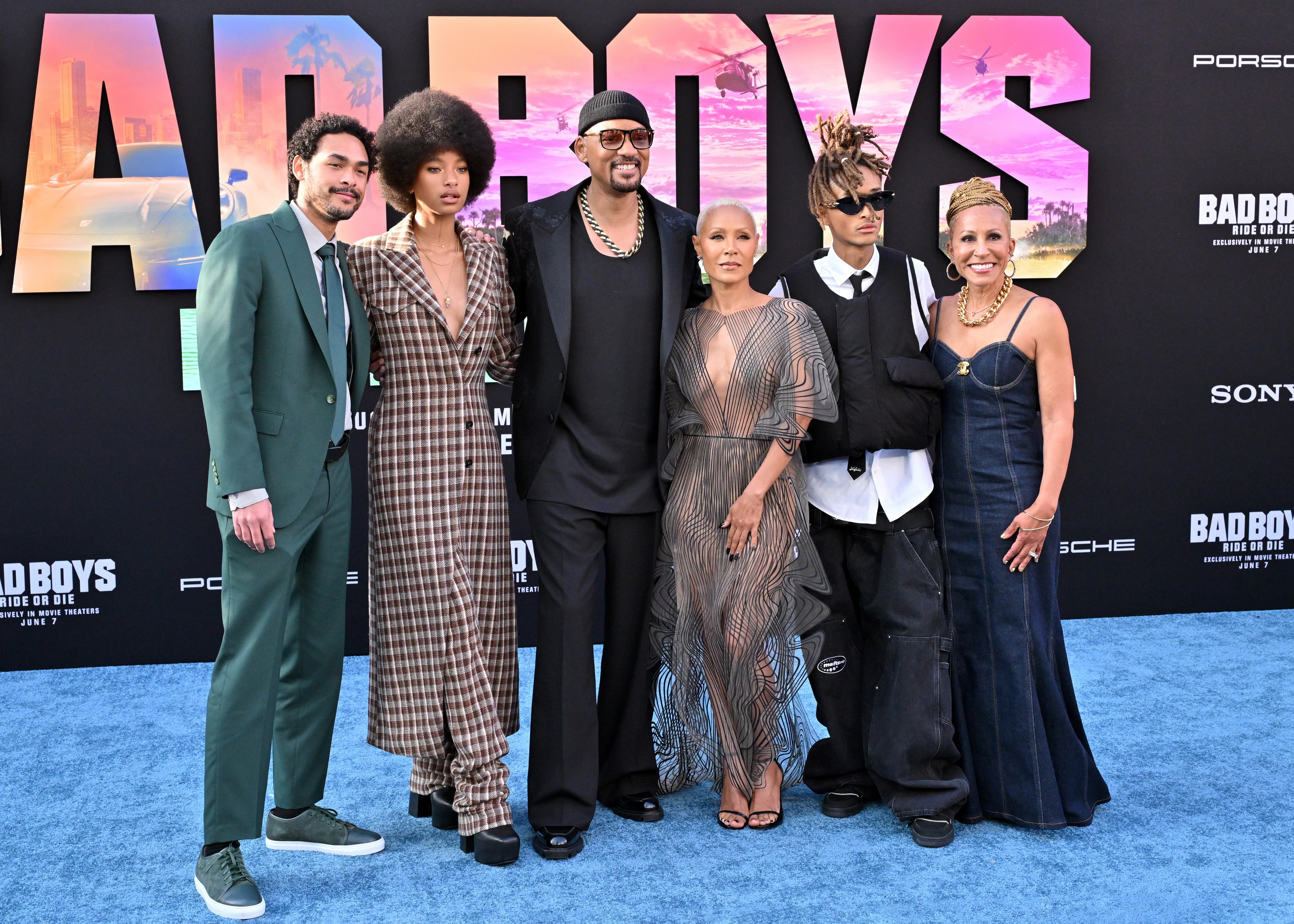 Group of radical   posing connected  the reddish  carpet, dressed successful  a assortment  of stylish outfits, immoderate   successful  suits and dresses, for a personage  event