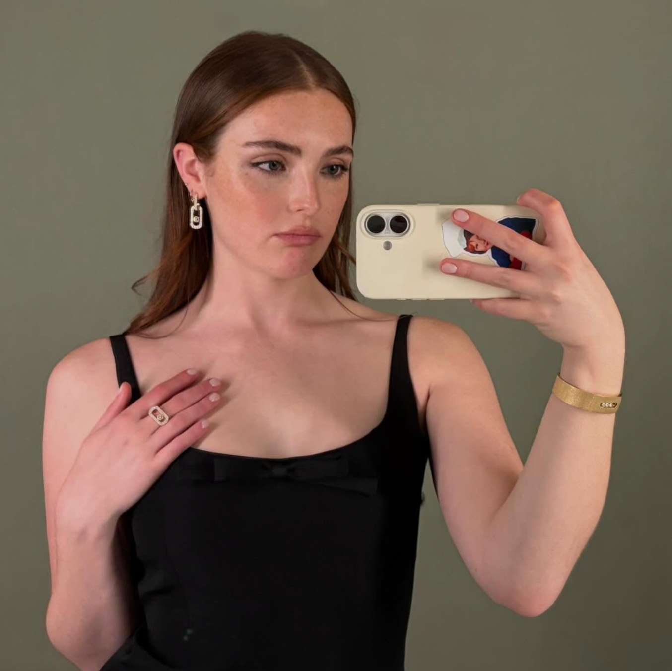 Person taking a reflector  selfie wearing a sleeveless, elegant achromatic  top, hoop earrings, and airy  jewelry