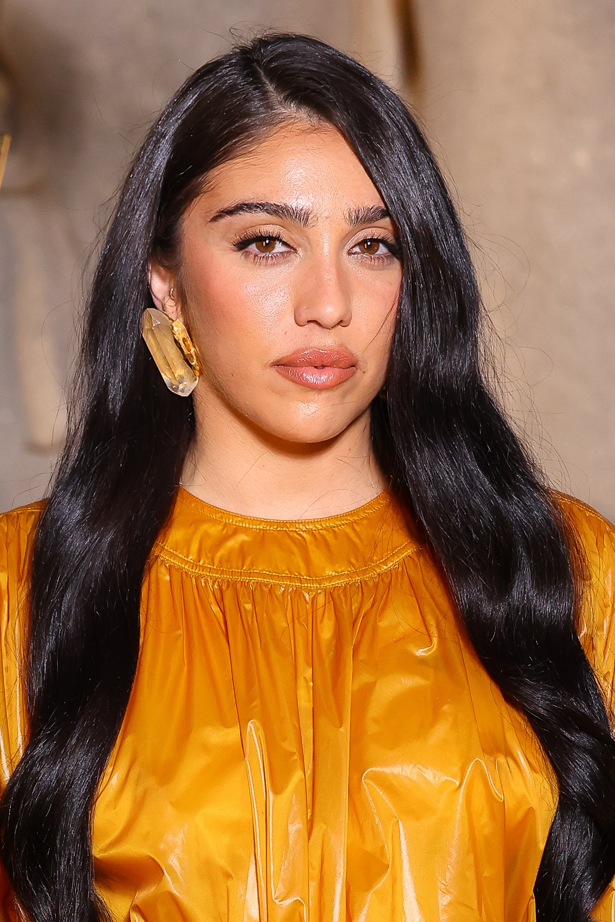 Person with agelong  acheronian  hair, wearing a shiny gathered apical  and connection    earrings, connected  a reddish  carpet