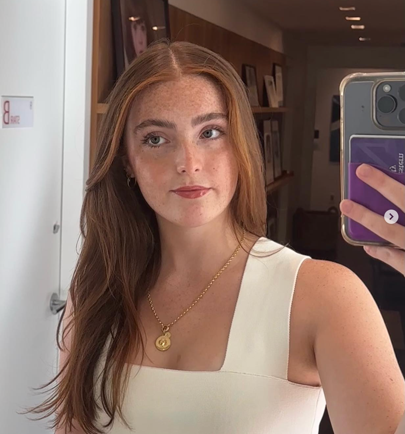 Person takes a reflector  selfie wearing a sleeveless apical  and pendant necklace, lasting  successful  a country   with framed photos connected  partition  shelves