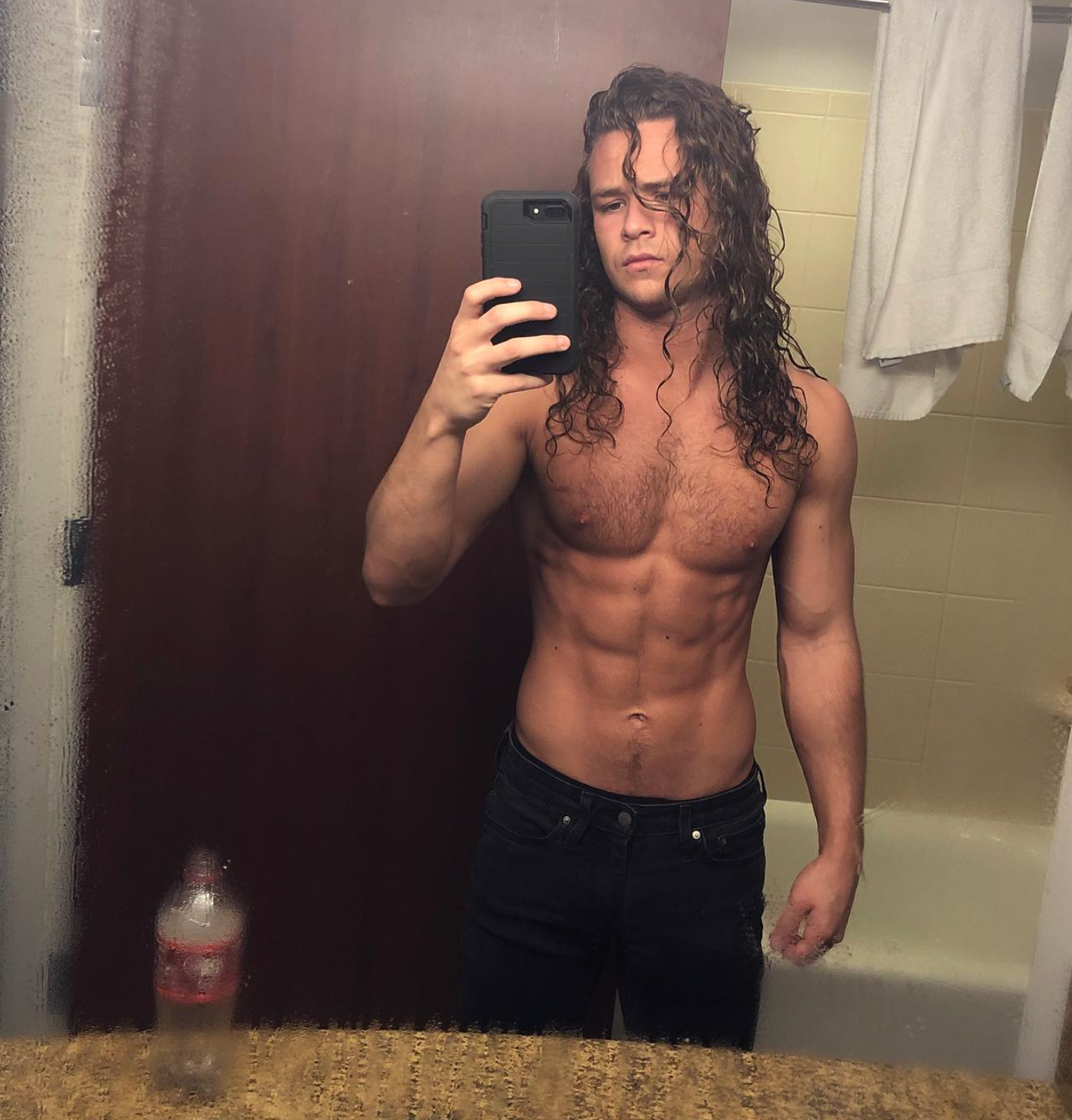 Person taking a reflector  selfie successful  a bathroom, showing agelong  hairsbreadth  and toned physique, wearing acheronian  jeans
