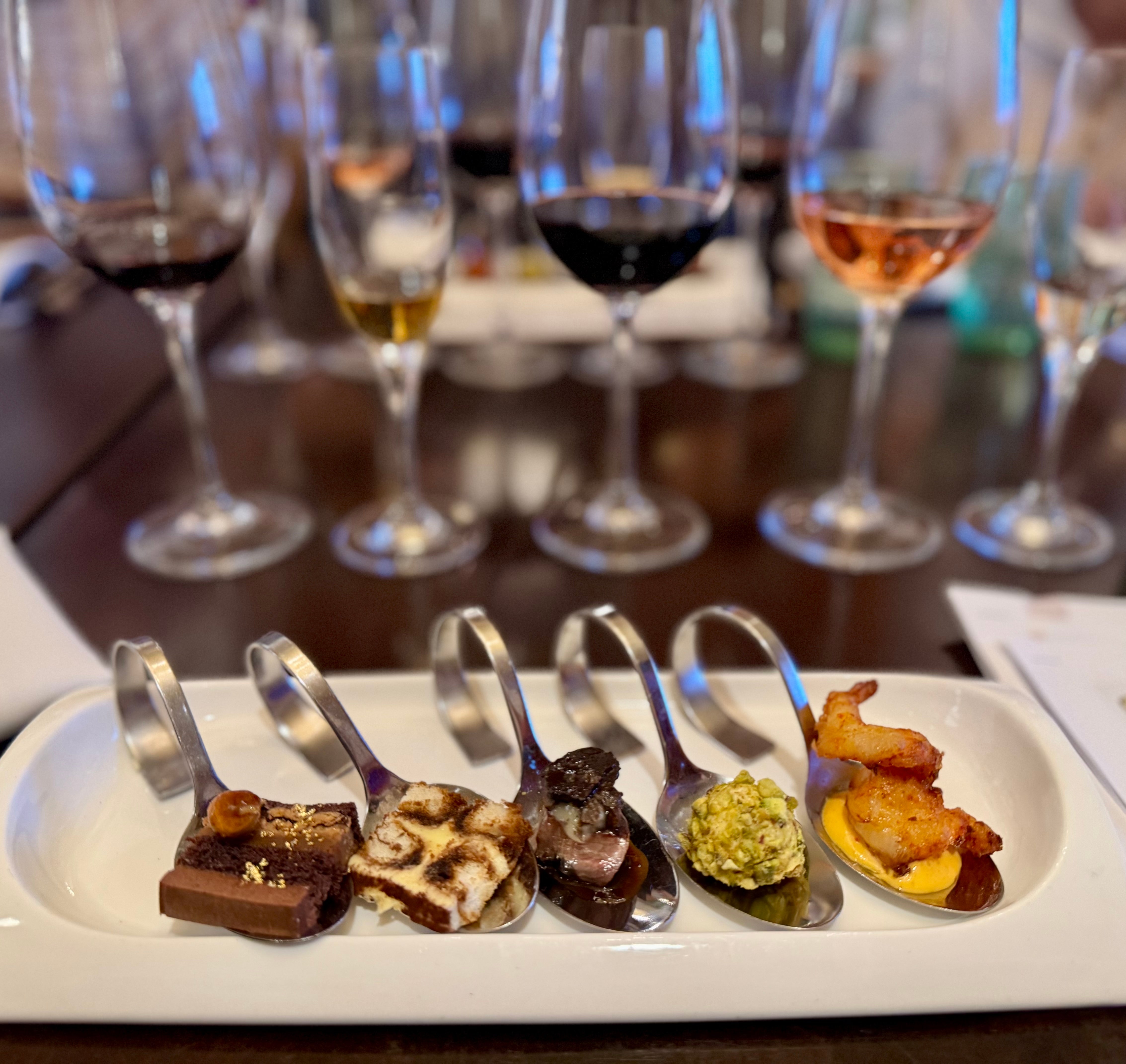 Five dishes connected spoons arranged successful a row, each paired with a antithetic vino successful the background