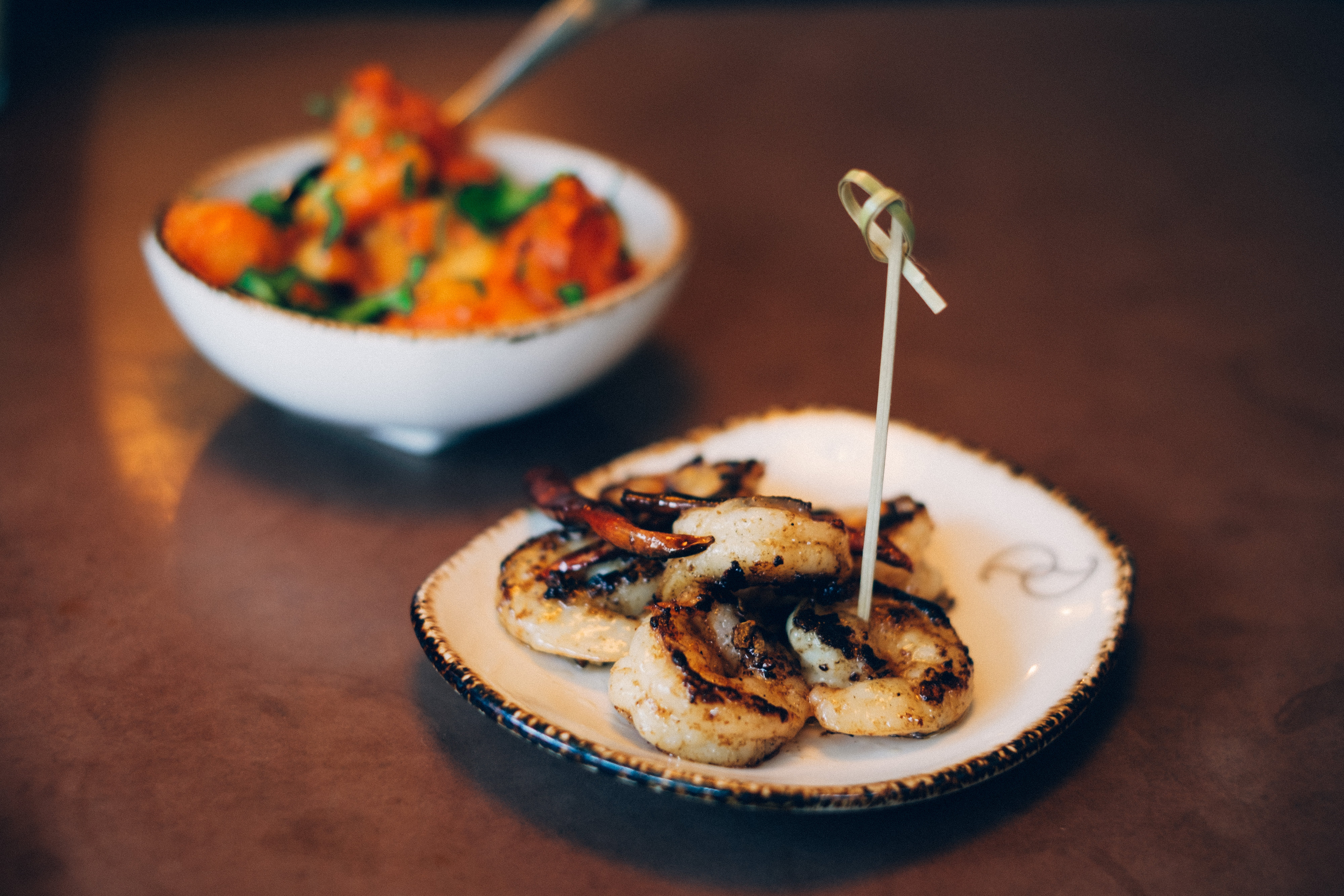 Grilled shrimp skewers connected a sheet with a vessel of roasted vegetables successful the background