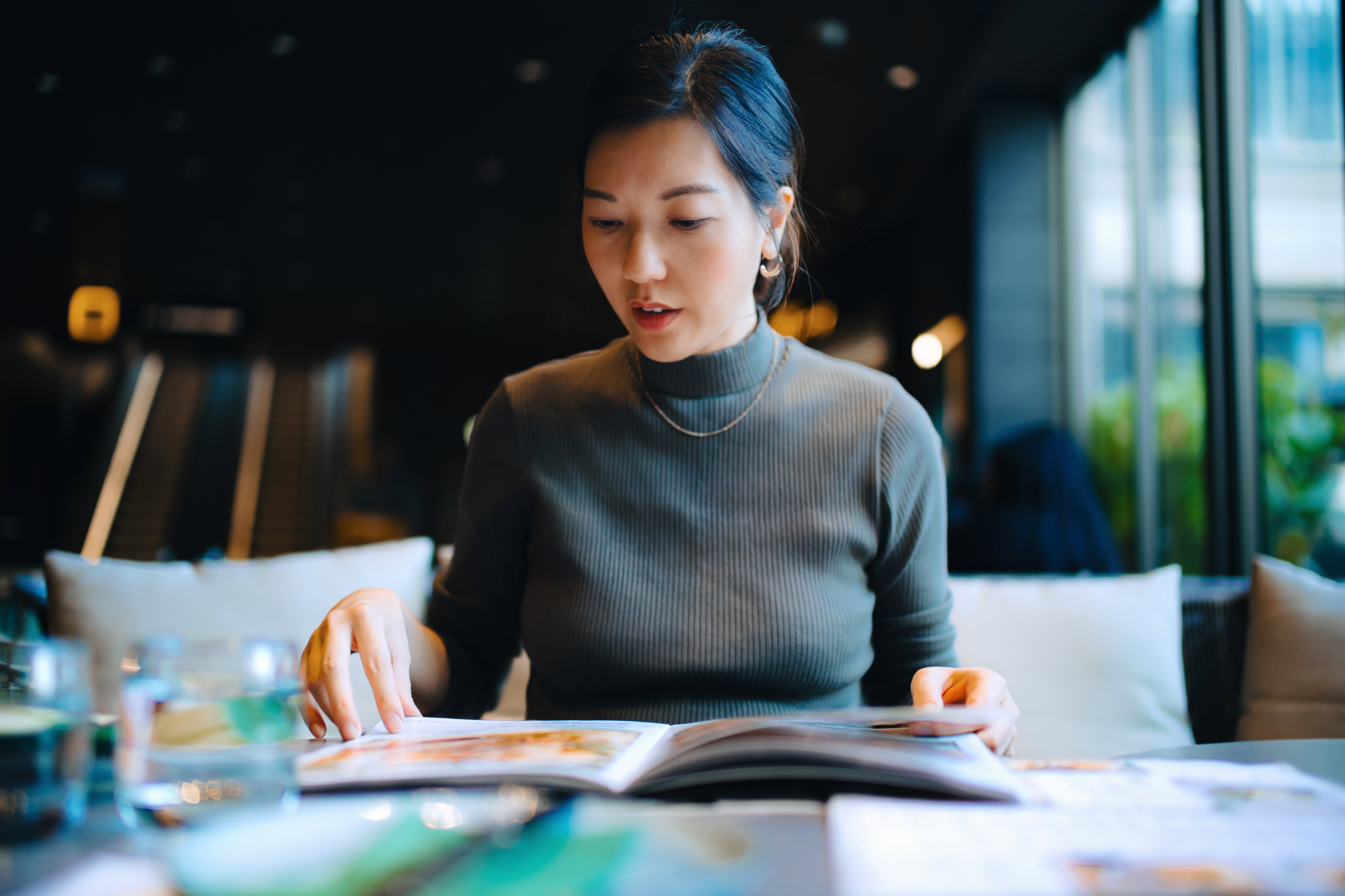 Person sitting astatine a edifice table, looking astatine a menu, with a thoughtful expression