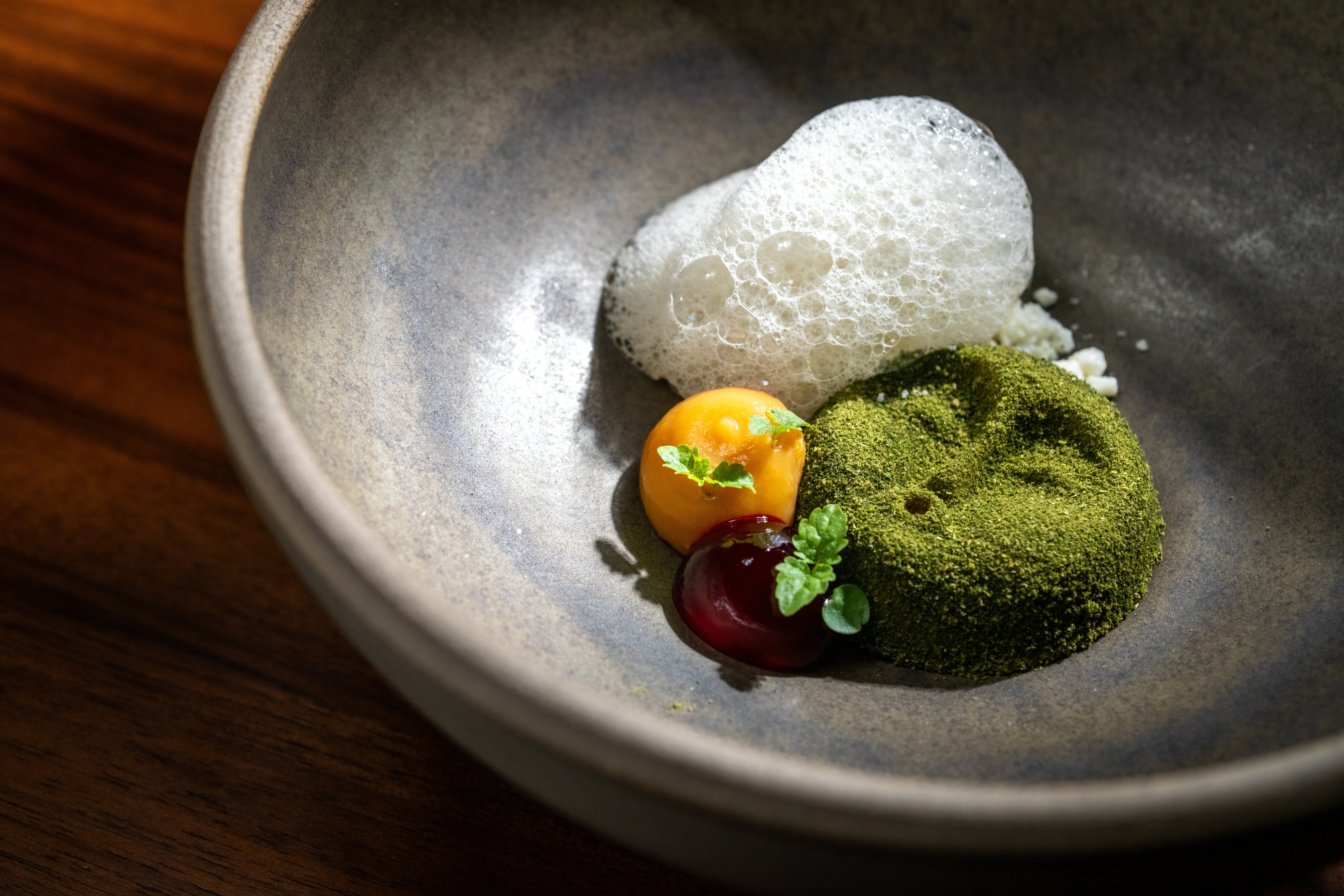 Gourmet crockery with foam, a greenish matcha-covered mousse, yellowish puree, reddish gel, and microgreens, elegantly plated successful a shallow bowl
