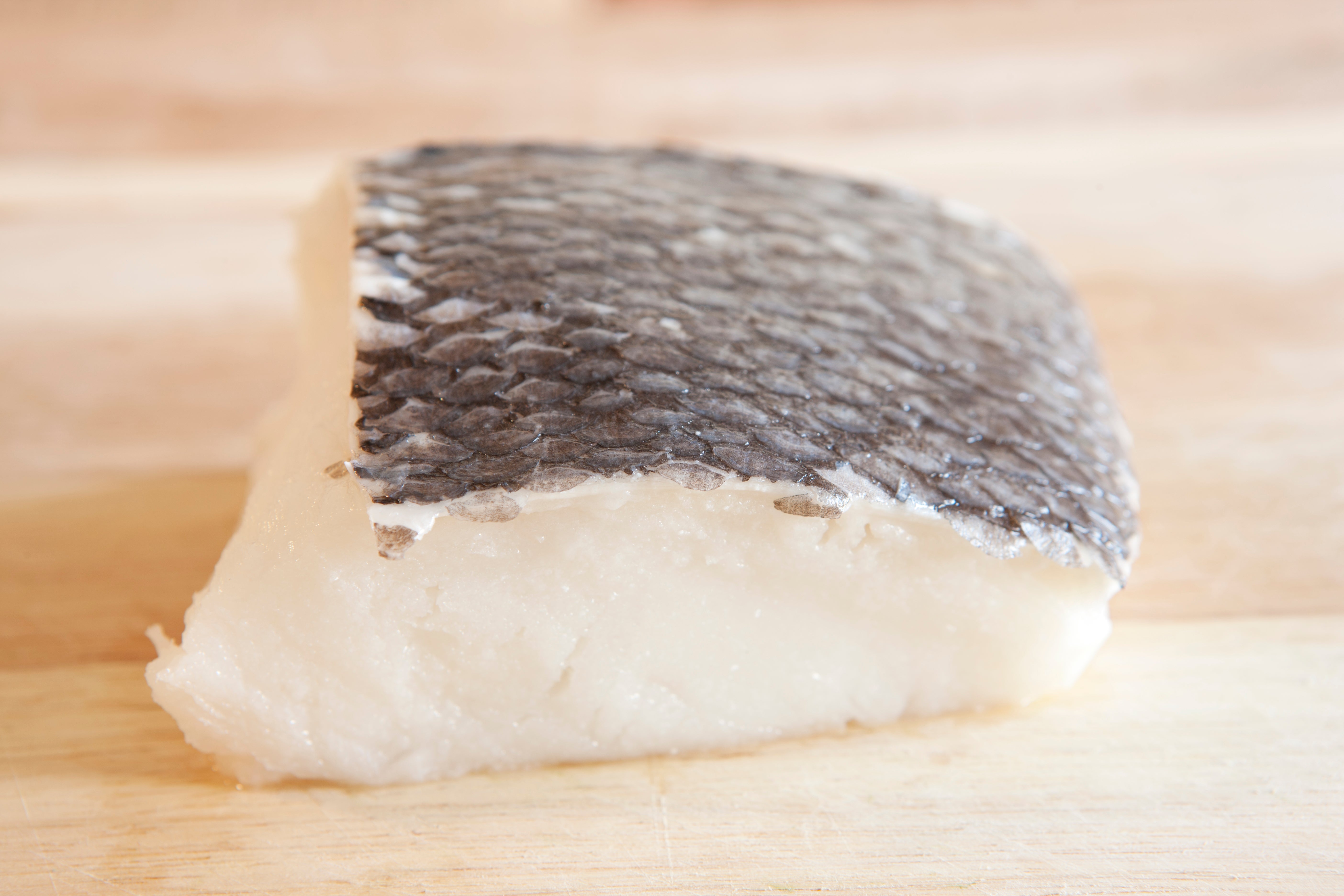 Raw food fillet with scaly tegument connected a woody cutting board