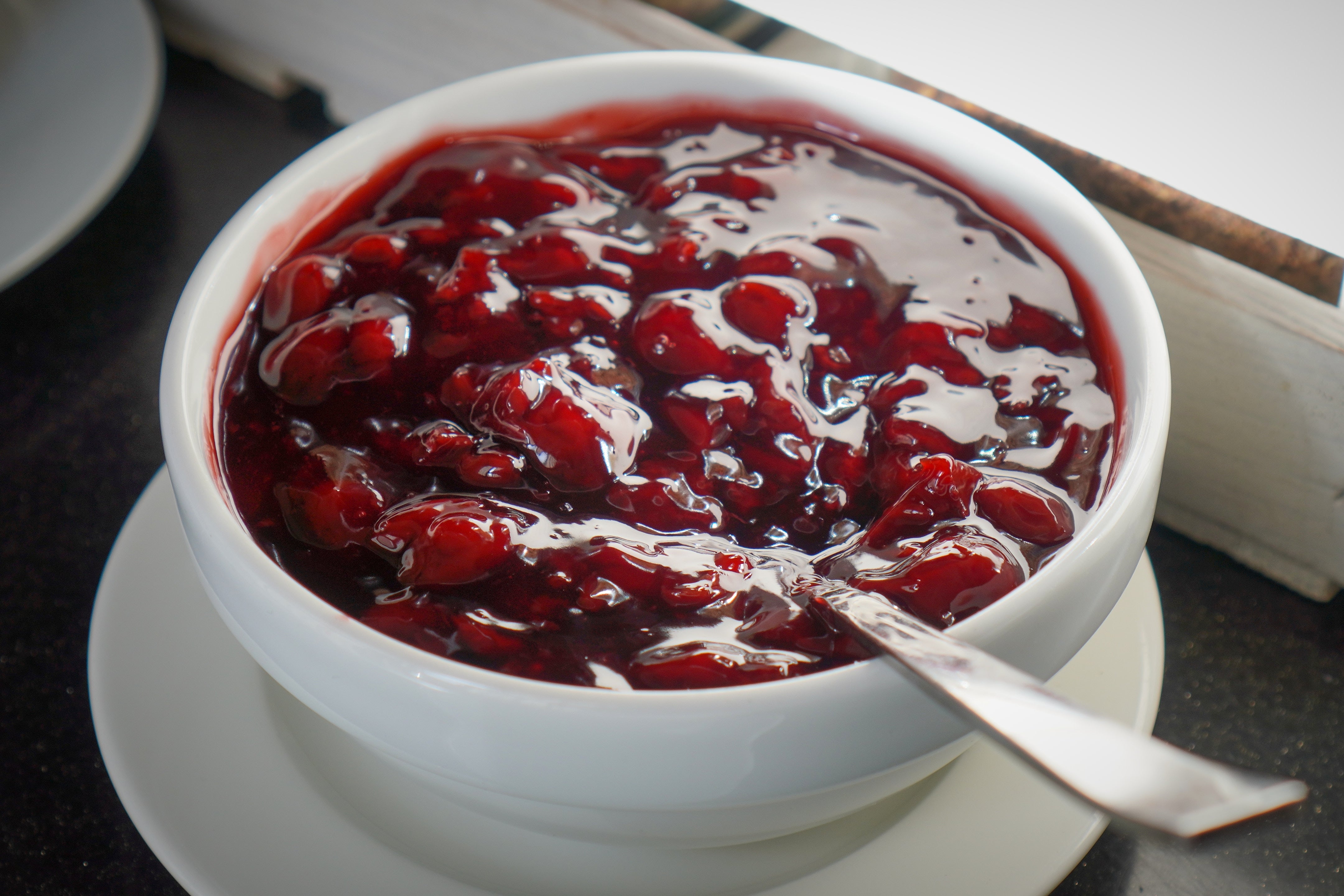 A vessel of cherry compote with a spoon, showing glossy cherries successful syrup, suitable for desserts oregon arsenic a topping