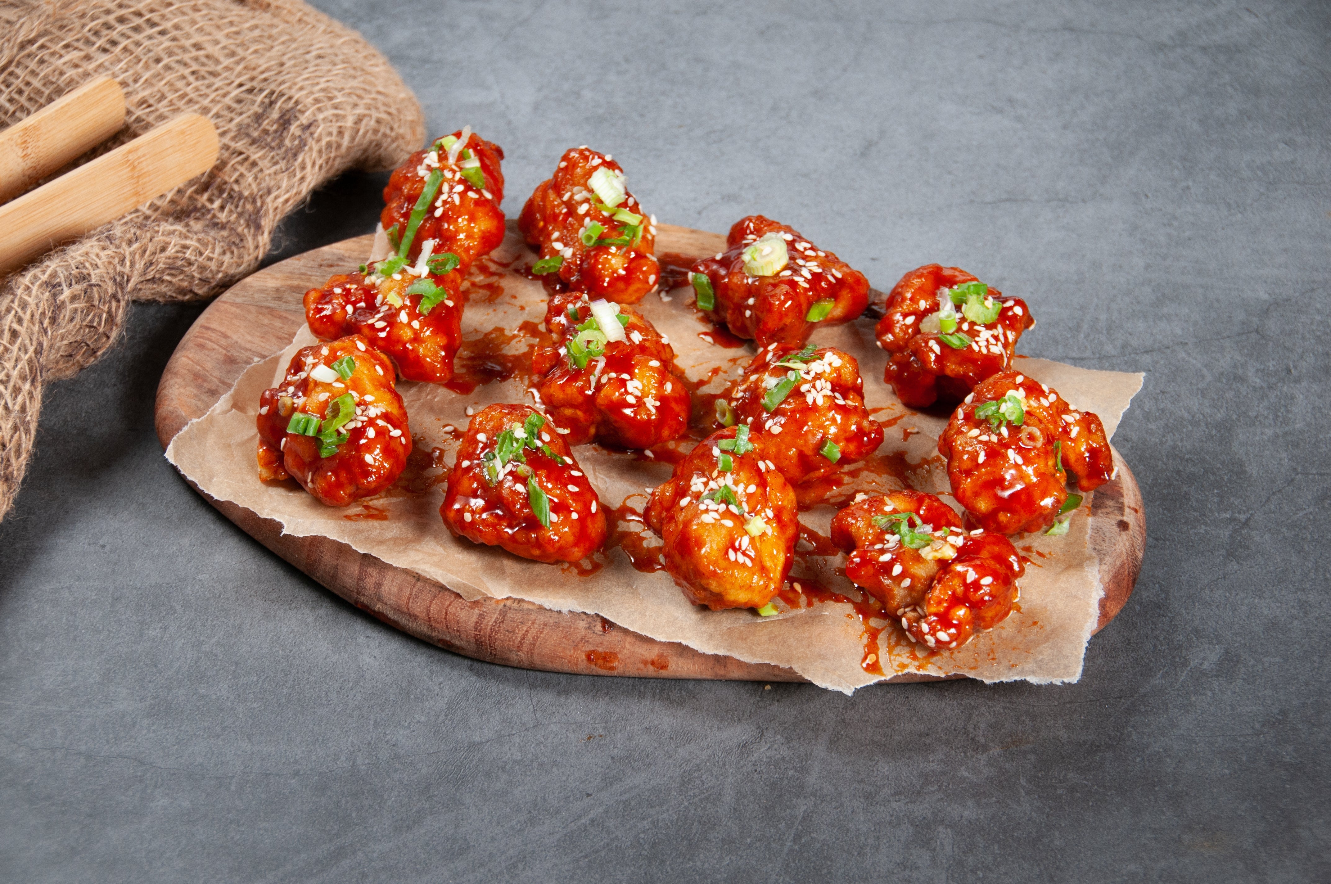 Saucy chickenhearted wings garnished with sesame seeds and chopped greenish onions connected a woody platter with parchment paper