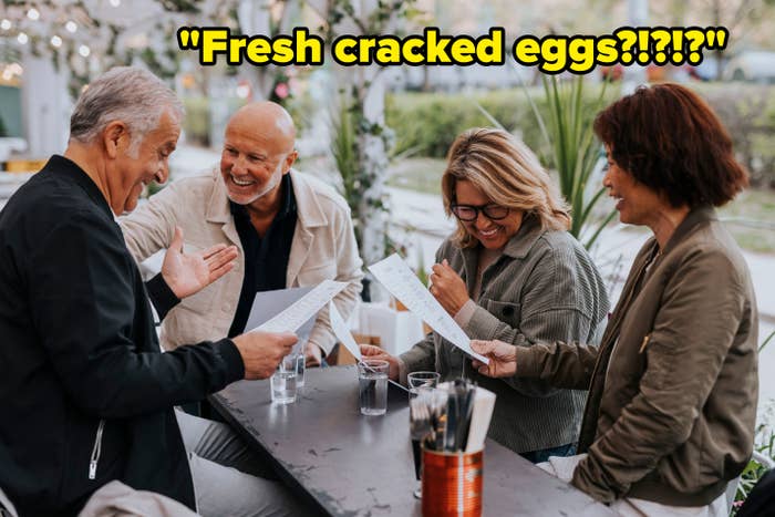 Four radical   smiling and looking astatine  menus portion    seated astatine  an outdoor table, suggesting a shared eating  acquisition   oregon  lively conversation