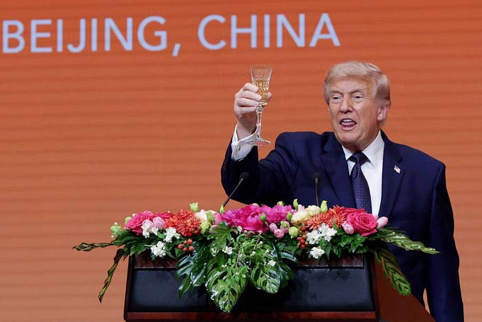 A idiosyncratic   successful  a suit   holds a toast astatine  a podium with flowers, nether  a backdrop with the substance   "Beijing, China."