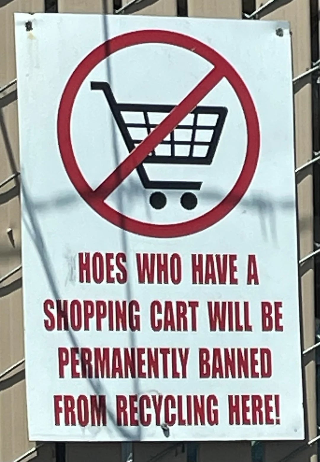 Sign with a red crossed-out shopping cart icon, reads: "HOES WHO HAVE A SHOPPING CART WILL BE PERMANENTLY BANNED FROM RECYCLING HERE!"