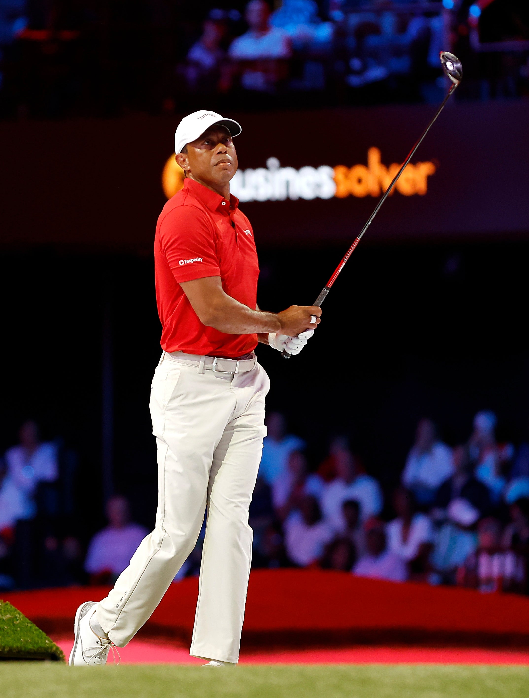 Tiger Woods in action, wearing a cap and sporty attire, swinging a club at a professional event