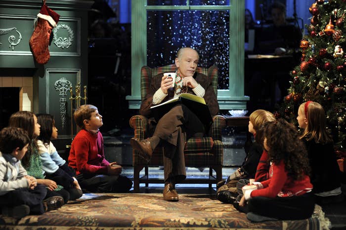 A idiosyncratic   successful  a seat  reads to seated children by a festive fireplace and Christmas histrion   connected  a TV set