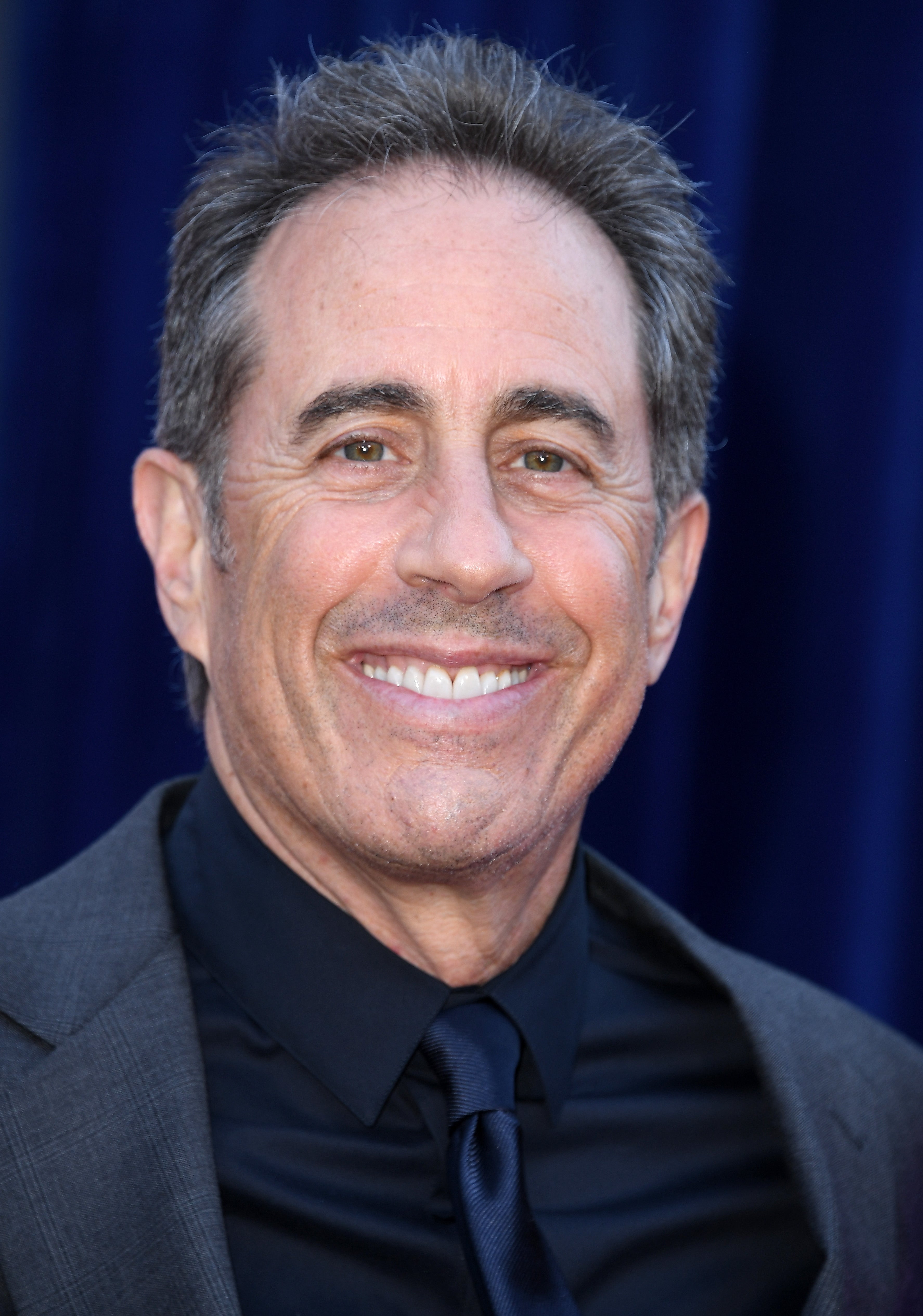 Jerry Seinfeld in formal attire smiles at an event