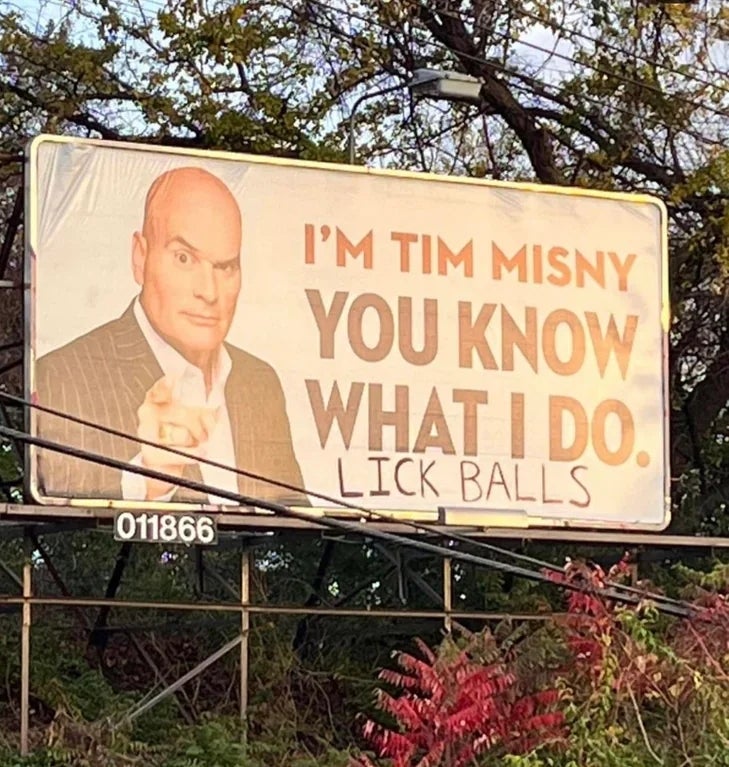 Billboard featuring "I'm Tim Misny, You Know What I Do" with an altered text below reading "Lick Balls."
