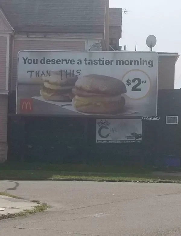 A billboard shows two breakfast sandwiches with the text altered to read, "You deserve a tastier morning than this" with price $2 each