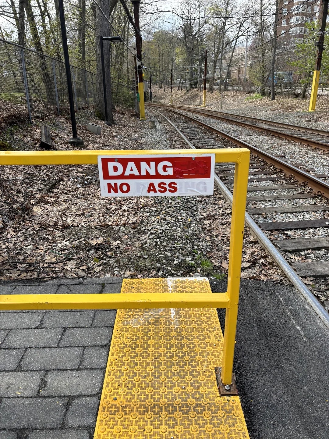 Sign on yellow barrier by train tracks reads, "DANGER NO TRESPASSING."