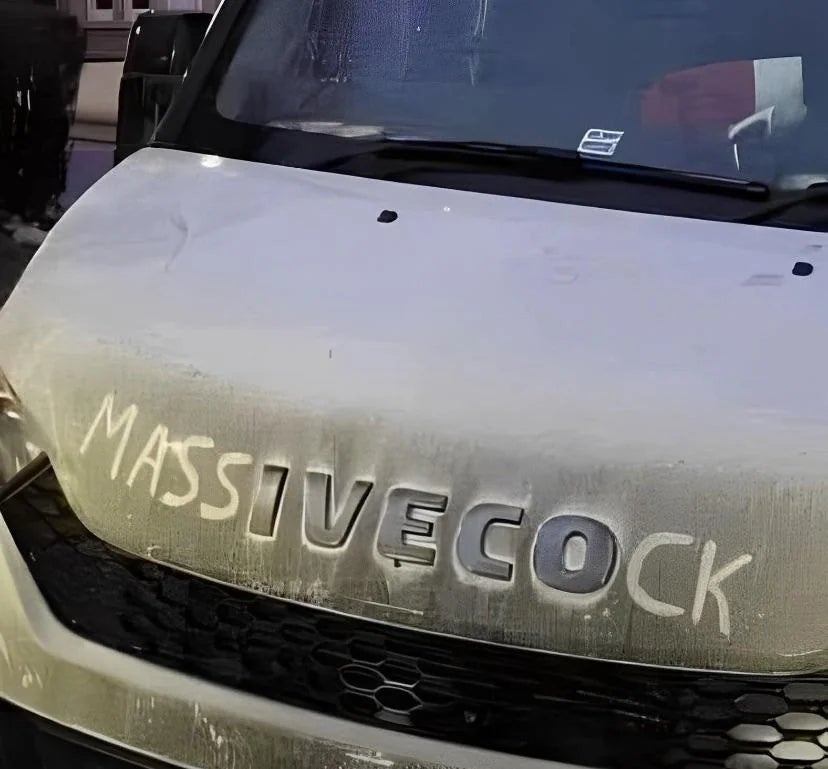 The word "Massivecock" is written in the dust on the hood of a vehicle