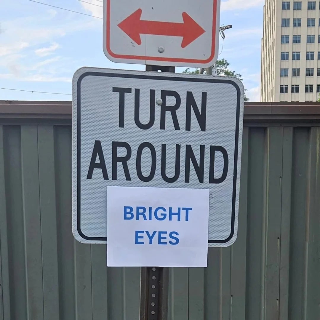 Sign reads "TURN AROUND" with an added paper below saying "BRIGHT EYES."