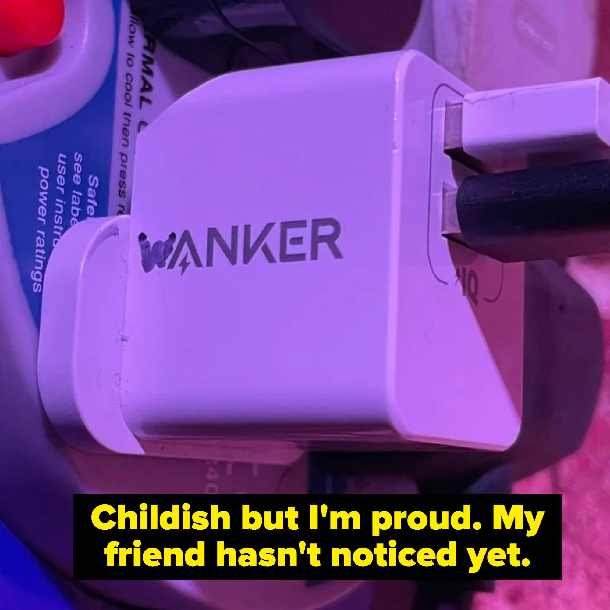 White electrical plug with the word "WANKER" on its side, placed among other electronic devices
