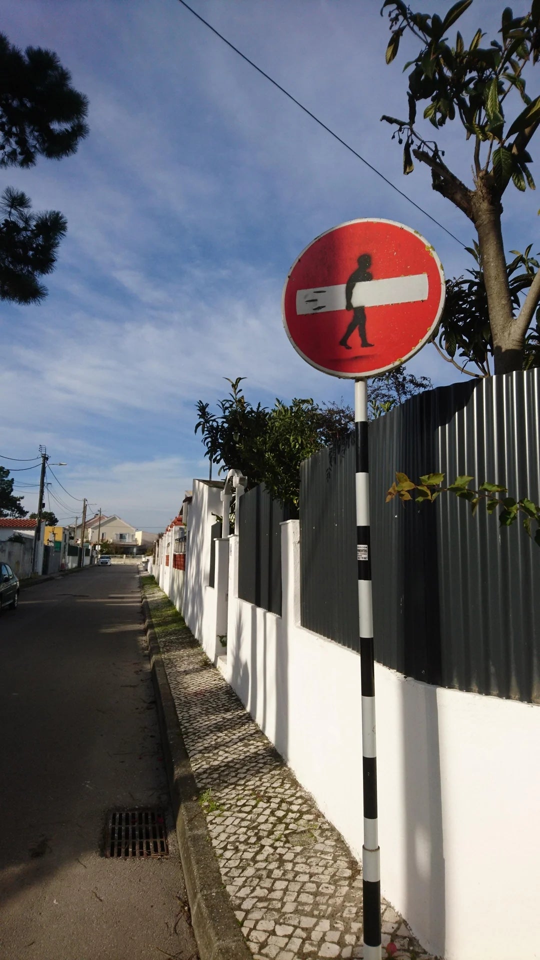 Street art on a "no entry" sign shows a silhouette of a person carrying the center as a plank