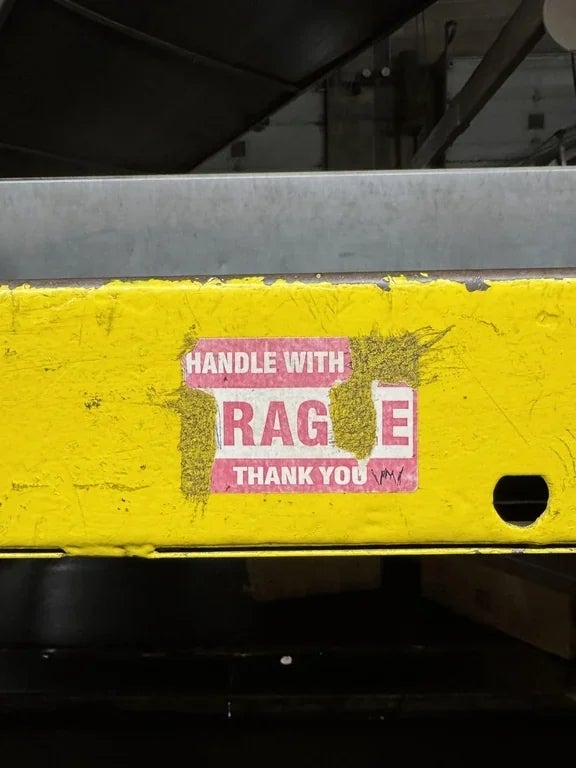 Damaged sticker on industrial equipment reads "Handle with Care, Fragile, Thank You." Some letters are missing, altering the message humorously