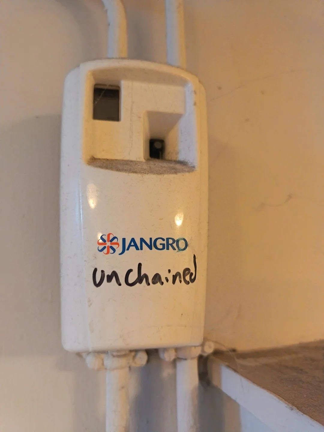 Wall-mounted device with the Jangro logo and "unchained" written below it