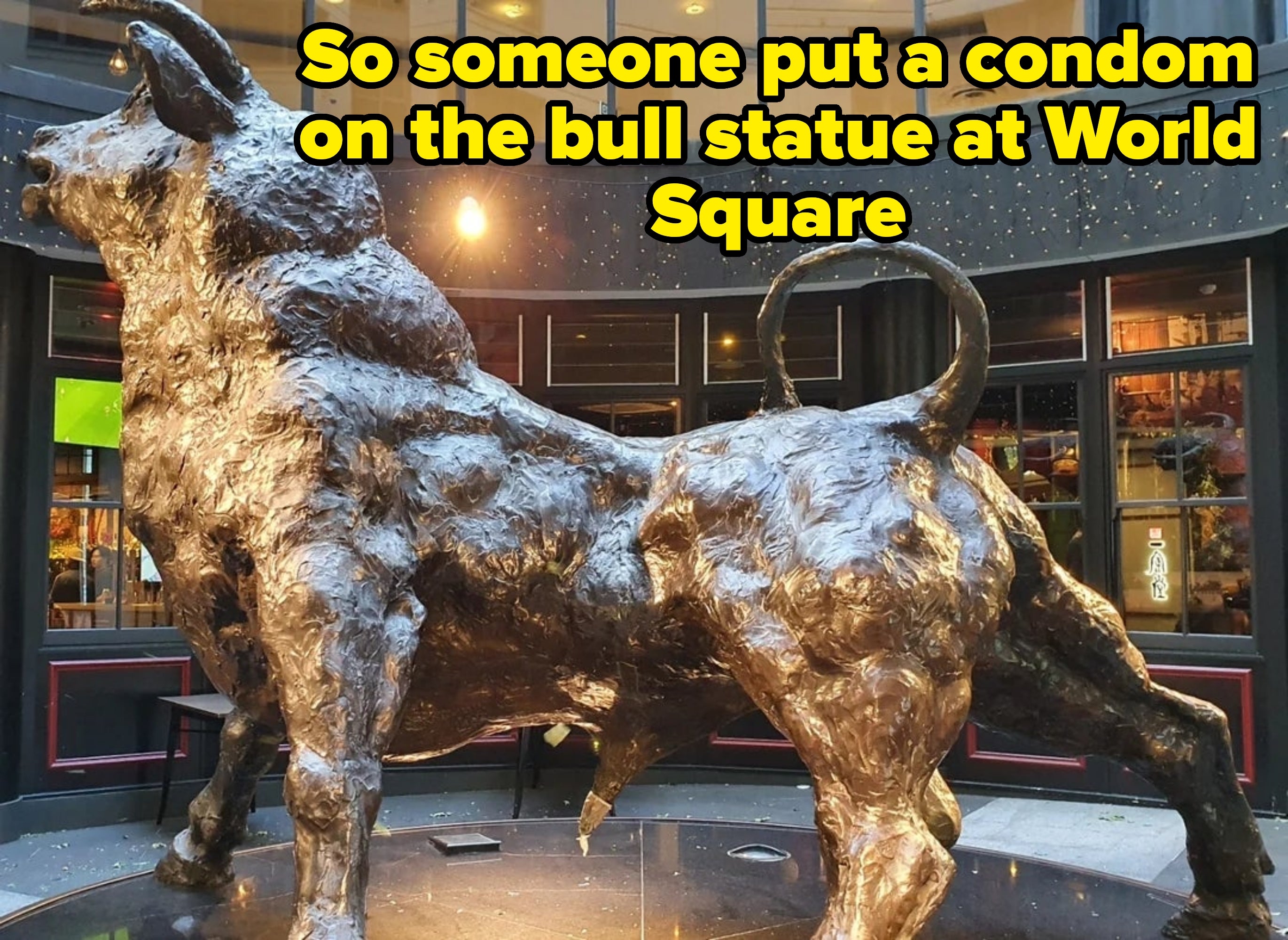 Bronze bull sculpture stands prominently in a public space, showcasing its muscular form and dynamic pose