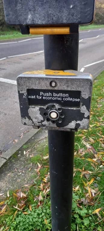 Crosswalk button with humorous sticker: "Push button, wait for economic collapse."