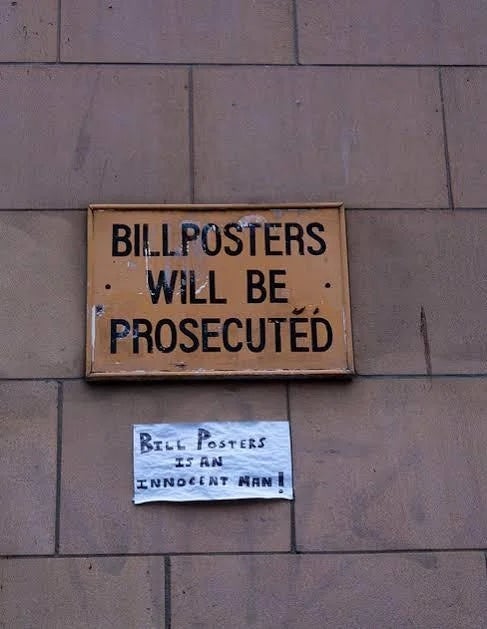 A sign reads "Billposters will be prosecuted," with a note below stating "Bill Posters is an innocent man!"