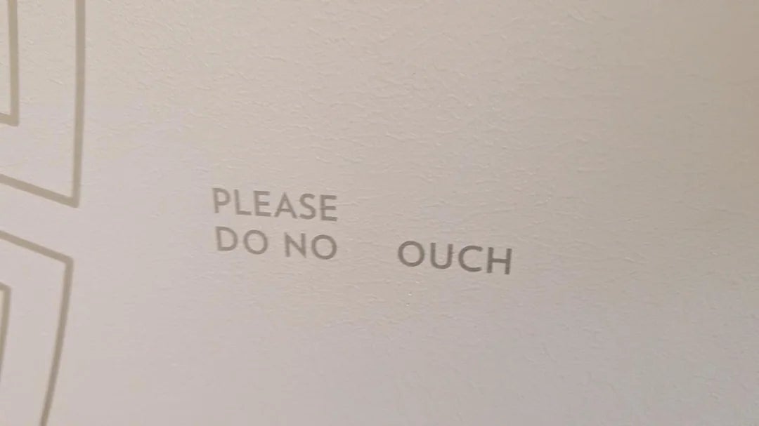 Text on wall reads: "Please do no ouch," likely a humorous typo or partial display missing a letter