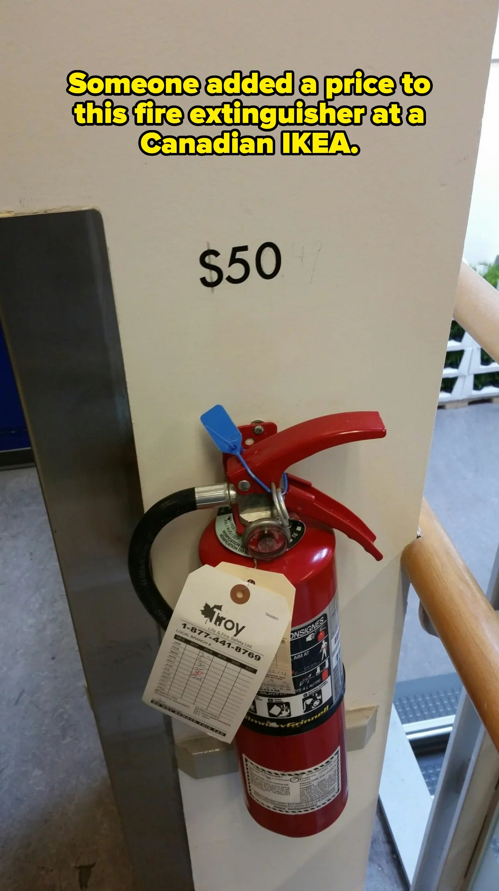 Fire extinguisher mounted on a wall with a tag. "$50" is written on the wall above it