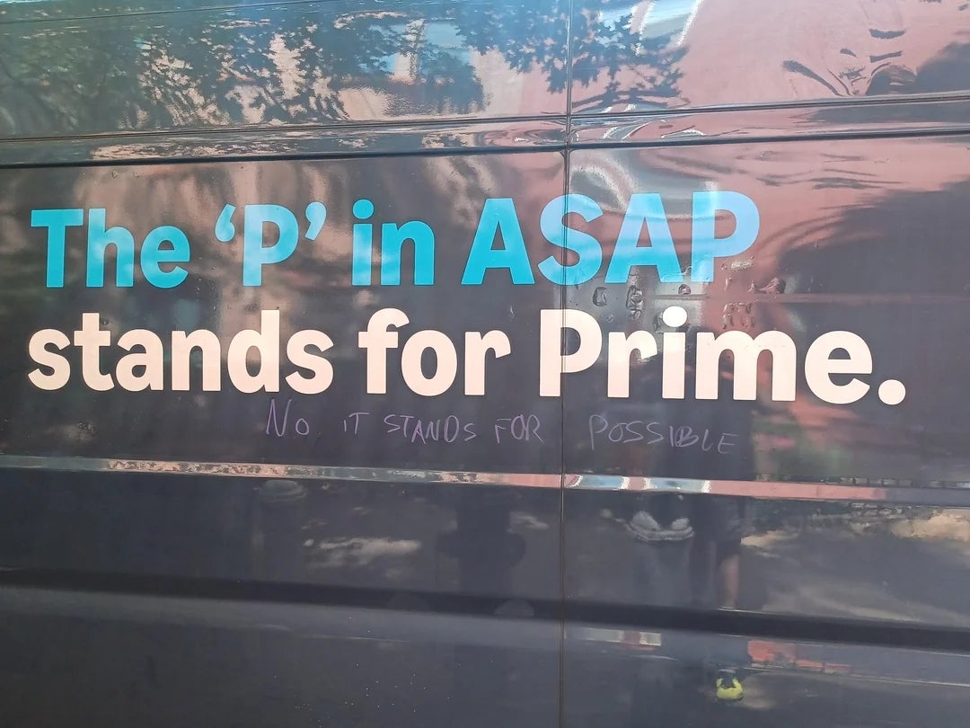 Graffiti on a truck reads "The 'P' in ASAP stands for Prime," with "NO IT STANDS FOR POSSIBLE" written underneath