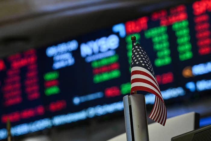An American emblem  successful  beforehand   of a blurred banal  marketplace  speech   committee  displaying numbers and NYSE ticker
