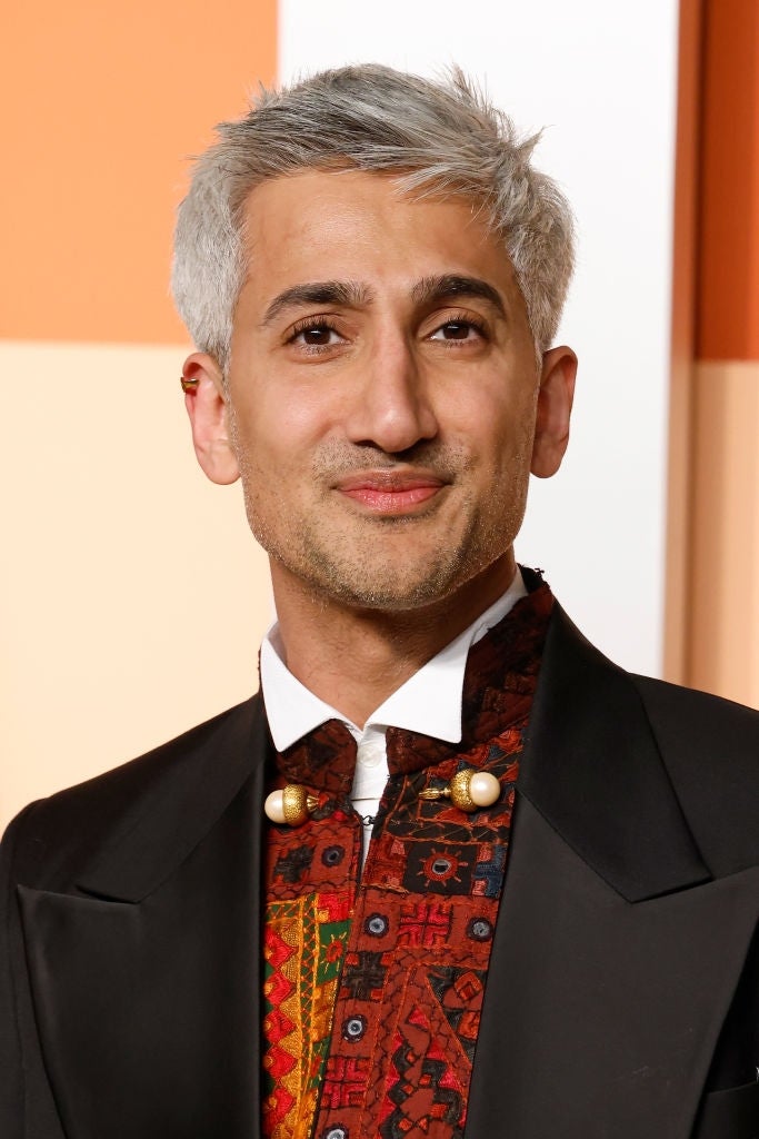 Person astatine  lawsuit   wearing a tailored suit   with a colorful patterned garment  and unsocial   buttons, smiling astatine  the camera