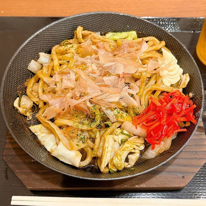丸亀製麺「丸亀焼きうどん やみつきソース味」の全体的な様子。キャベツや紅ショウガ、かつお節がトッピングされている。