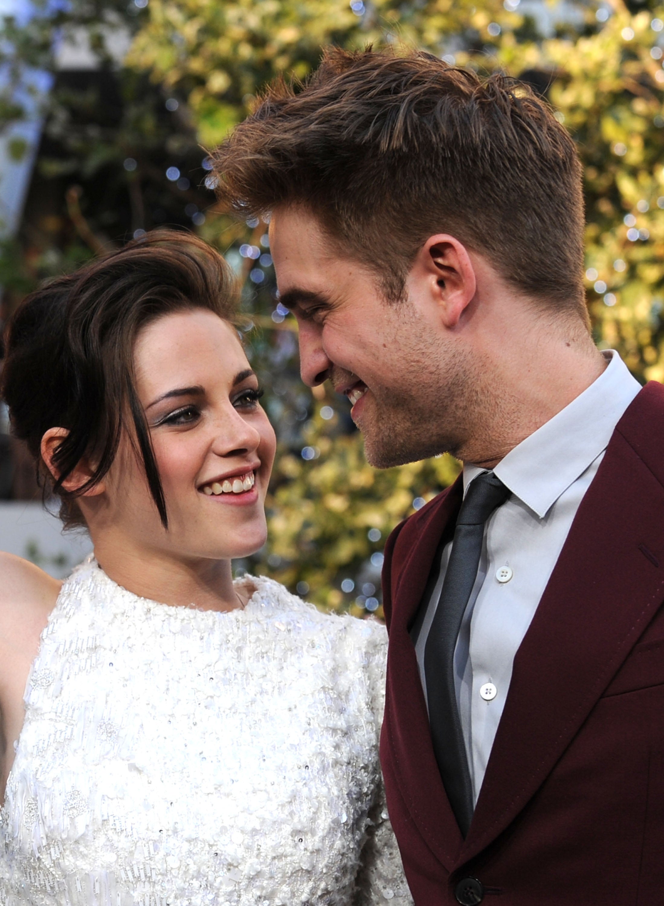 Kristen Stewart and Robert Pattinson smiling astatine  each   different   connected  a reddish  carpet.