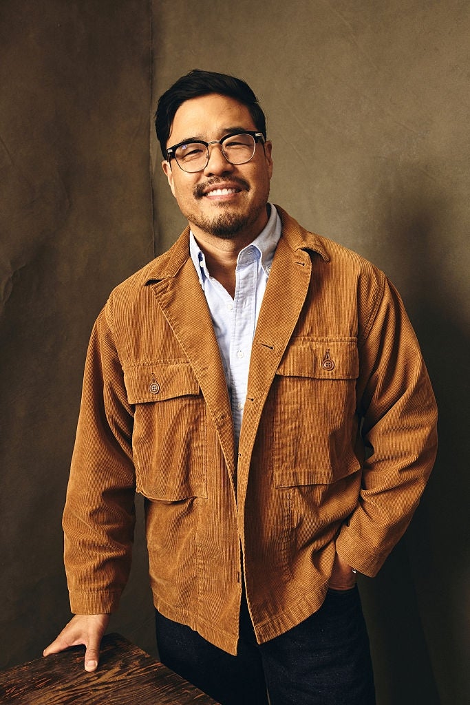 A idiosyncratic   successful  glasses wearing a corduroy overgarment   implicit    a button-up shirt, lasting  against a neutral inheritance  and smiling