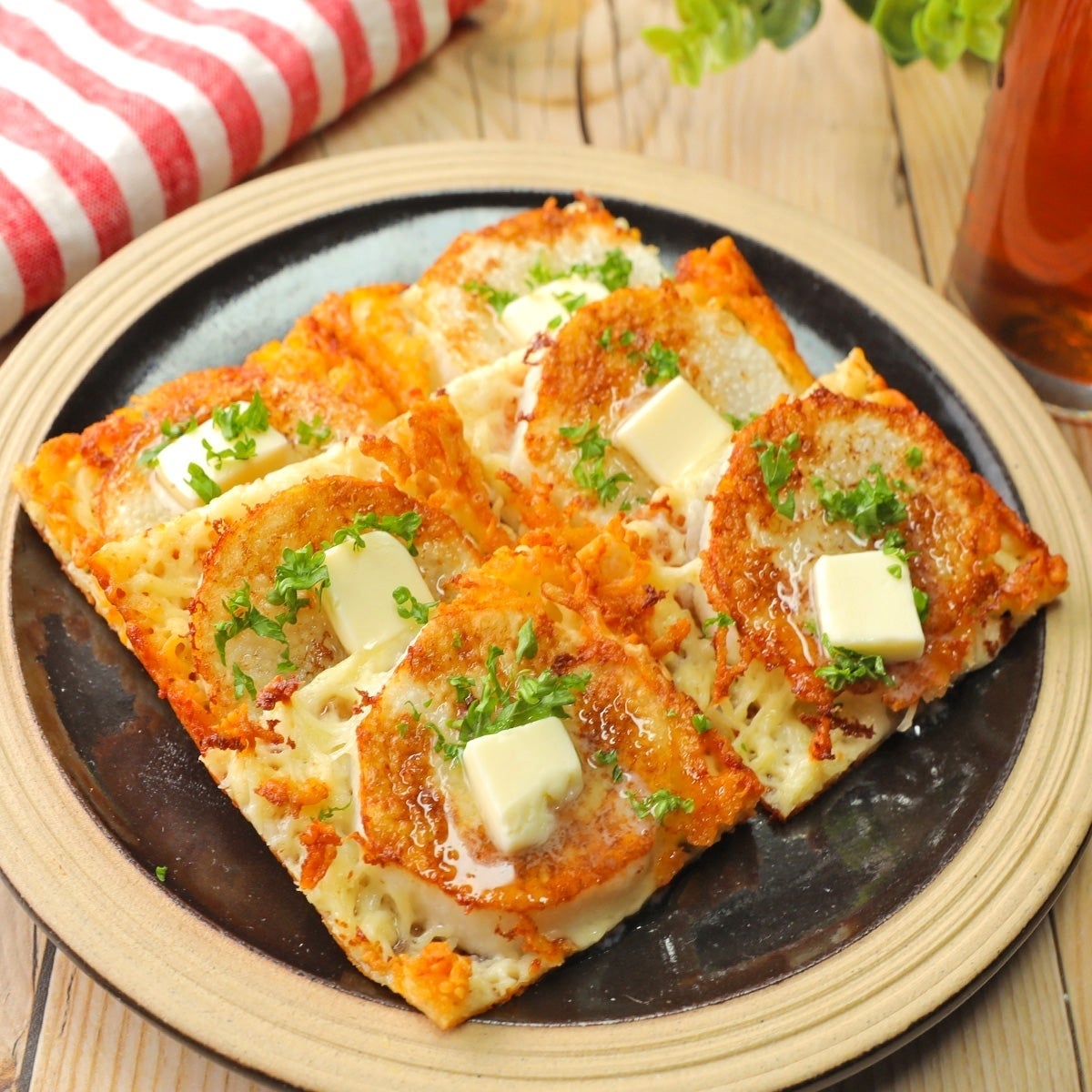 お皿にのった料理。トーストにチーズ、焼きトマト、パセリ、角切りバターがトッピングされている。