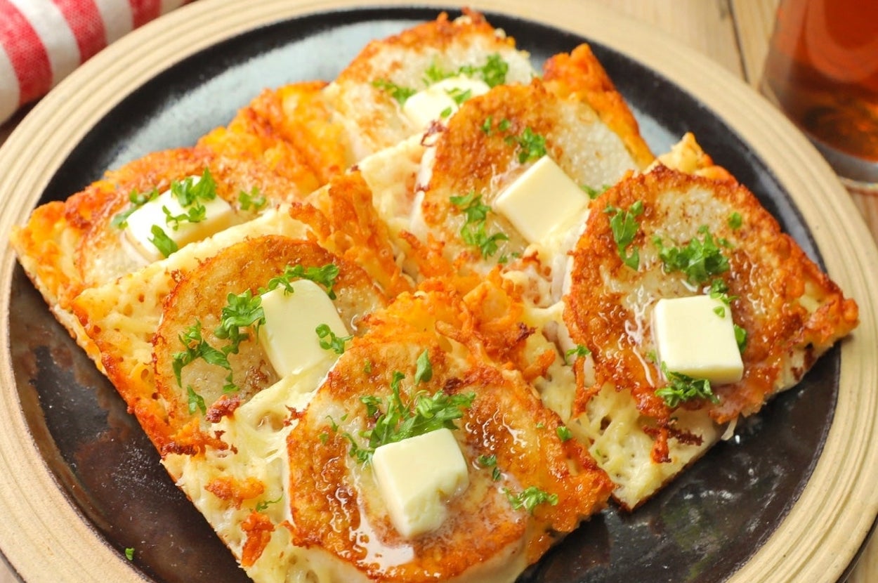 お皿にのった料理。トーストにチーズ、焼きトマト、パセリ、角切りバターがトッピングされている。
