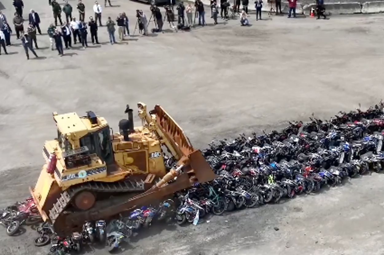 ブルドーザーが列になったバイクを押しつぶしている様子を上から撮影した画像です。
