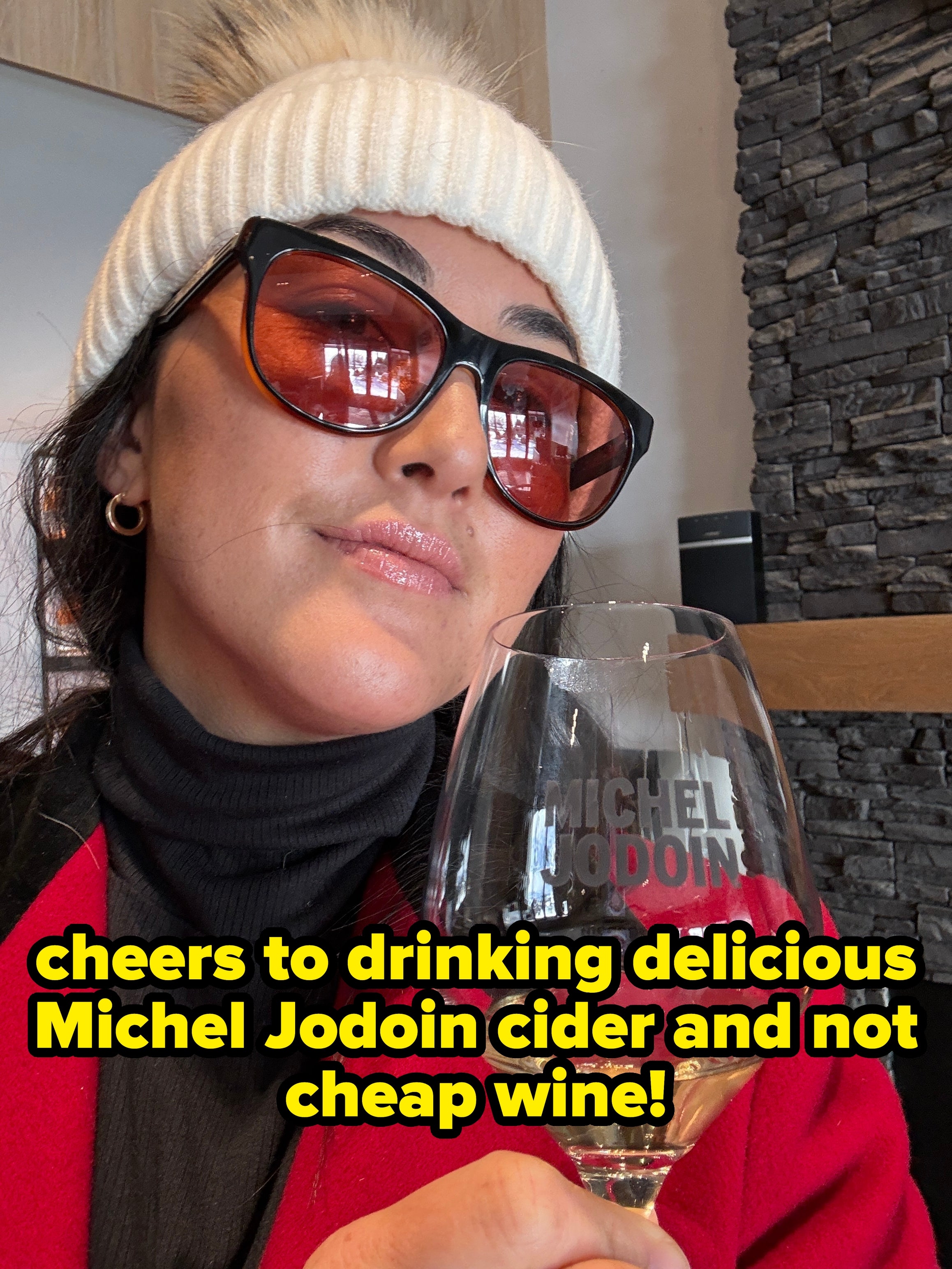 Person wearing sunglasses and a knit chapeau holds a vino solid astatine a winery, suggesting a wintertime question experience