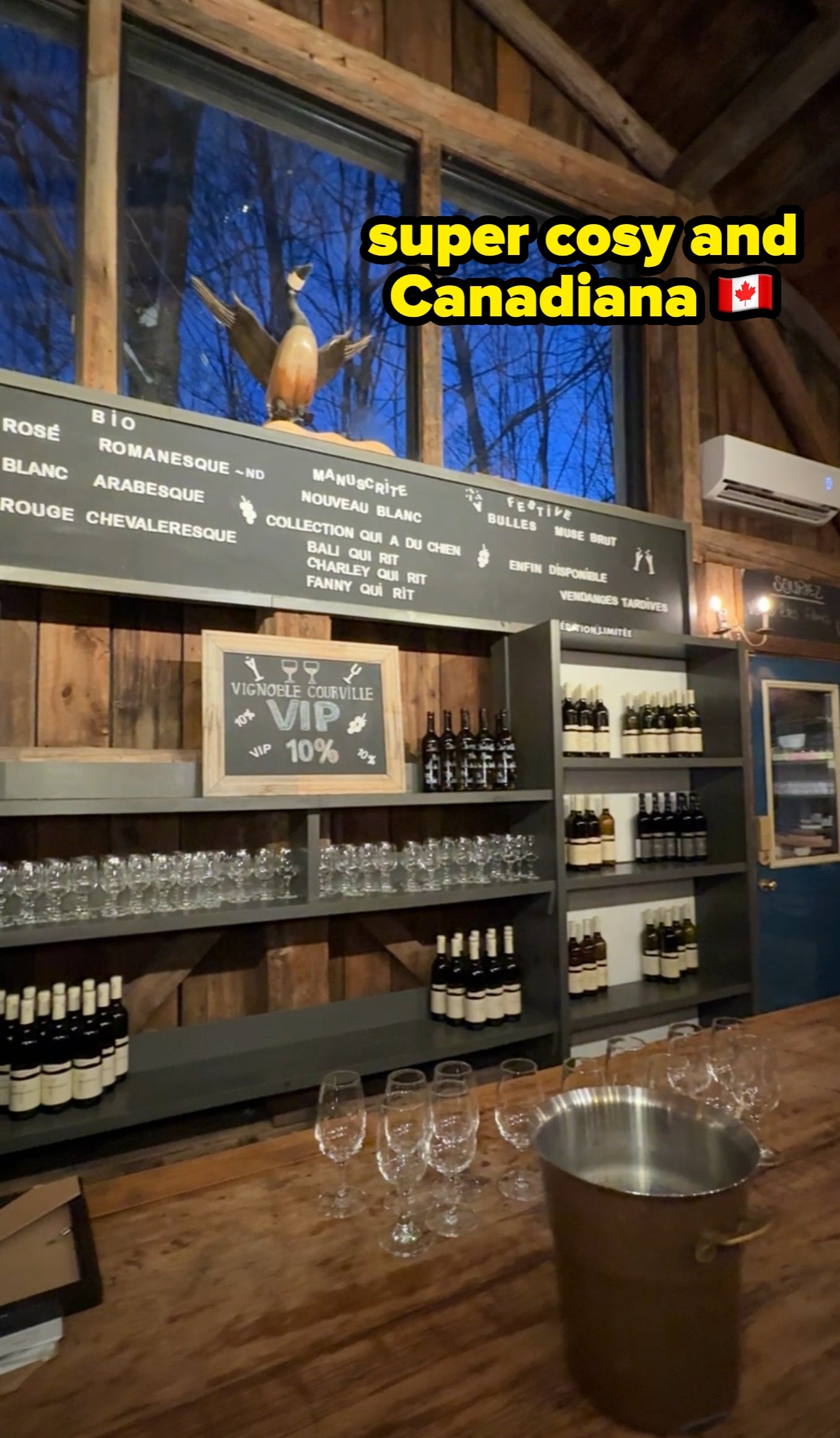 Rustic winery interior with a woody bar, vino bottles connected shelves, and glasses acceptable retired for tasting. Antlers and paper committee displayed above