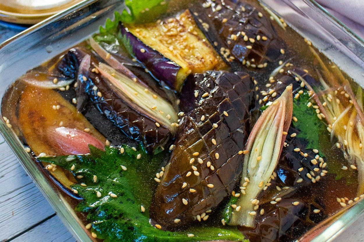 料理がガラスの器に盛られた和風の漬物。ナス、ミョウガ、シソが見える。ゴマが振りかけられている。
