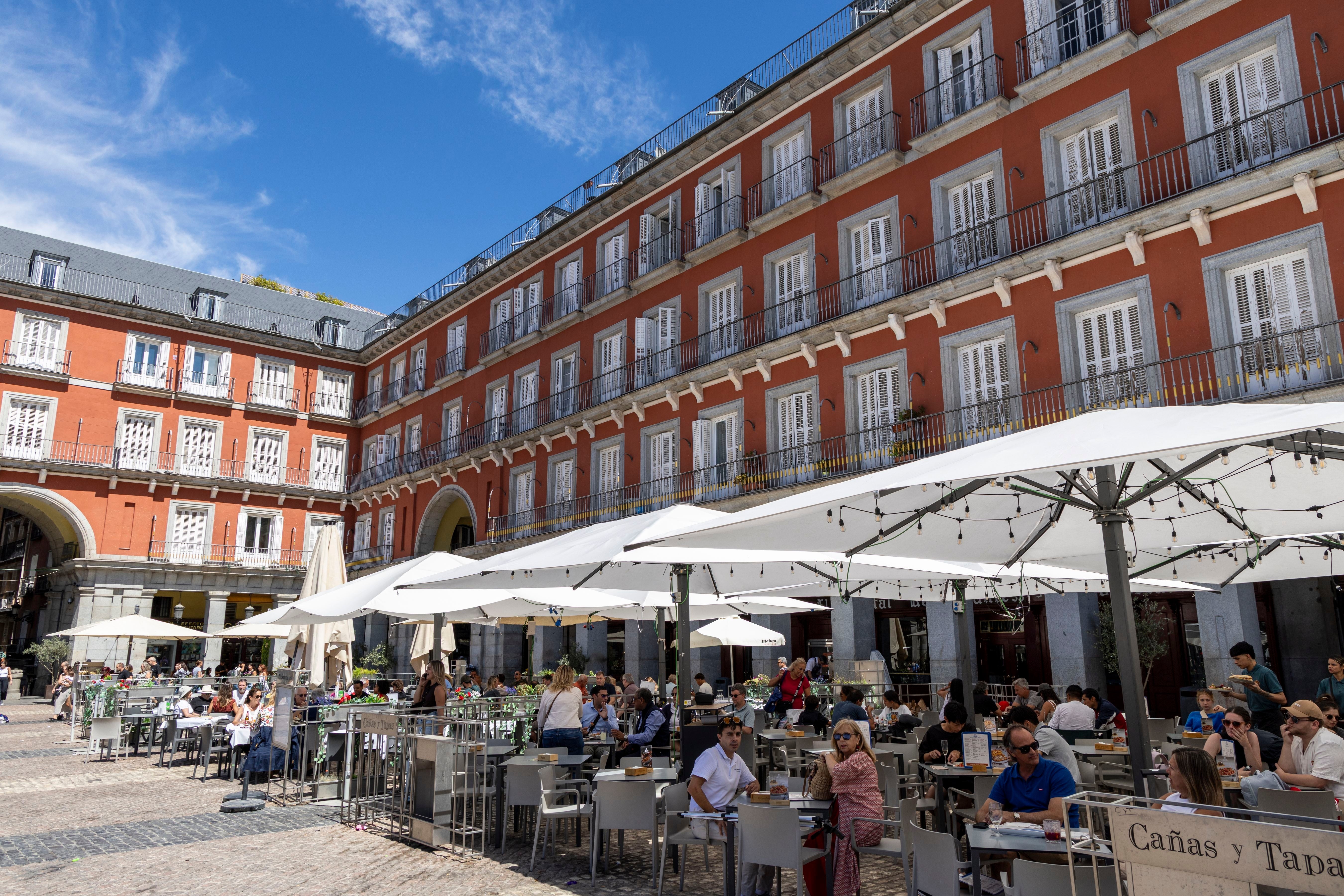 Outdoor café successful a lively plaza, surrounded by historical architecture and radical enjoying meals nether umbrellas, suggesting a vibrant question destination
