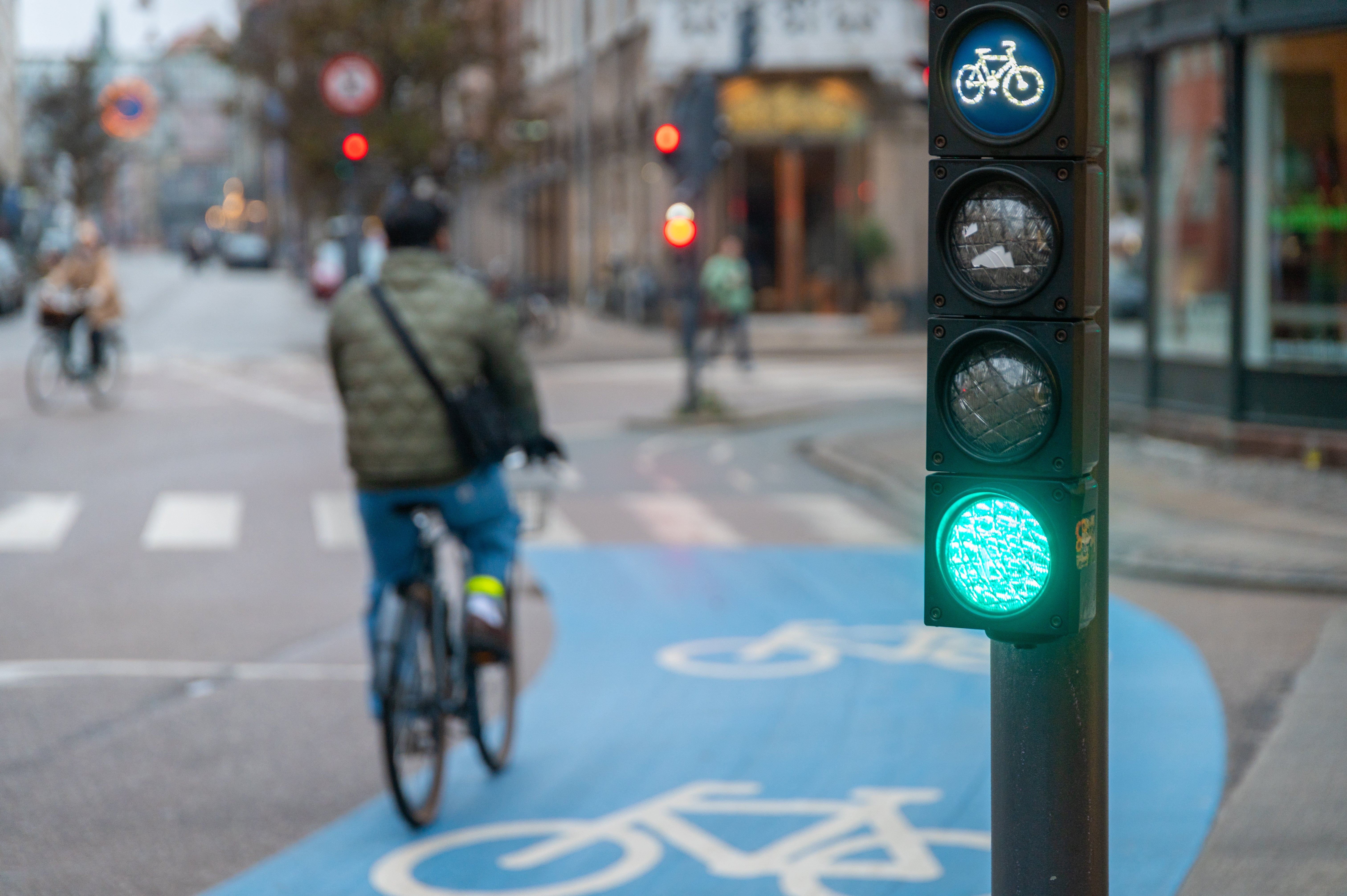 Cyclist riding connected a motorcycle way successful a city, with a greenish motorcycle postulation awesome indicating the close of way